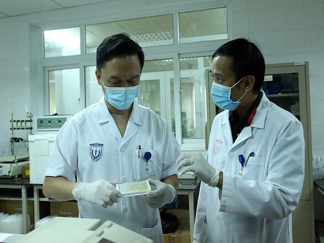 PGS.TS Hồ Anh Sơn (bên trái) xem xét mẫu xét nghiệm sinh kháng thể của các tình nguyện viên tiêm thử nghiệm. Ảnh: VGP/Đình Nam